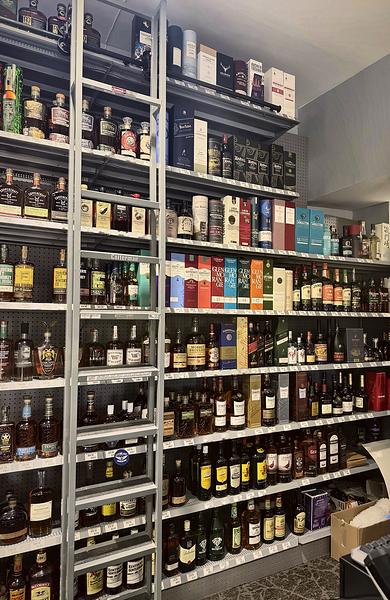Top shelves of boxed single malt Scotch reached by a rolling library ladder